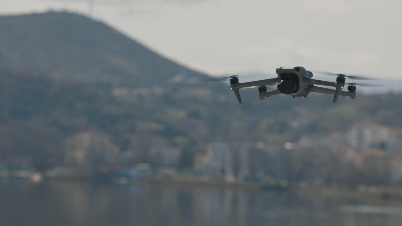 una toma de movimiento de gimbal suave de un avión no tripulado volador, montañas forestales con una pequeña ciudad en el fondo, clima de mal humor, cámara lenta video 4k