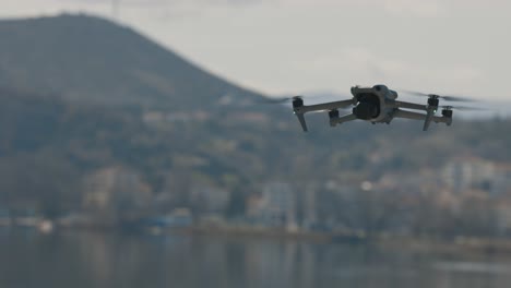 a smooth gimbal movement shot of a flying drone, forest mountains with a small town in the background, moody weather, slow motion 4k video