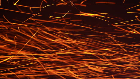 red hot sparkles of fire flying horizontally at a very fast speed. orange particles isolated on the black background.
