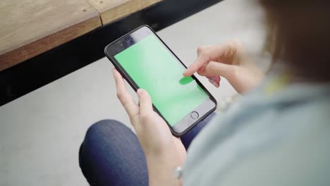 cheerful happy asian young woman sitting in cafe using smartphone device with green screen for talking, reading and texting. women lifestyle concept.