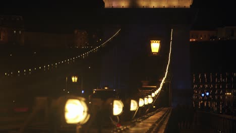 bright lights lined at the famous szechenyi chain bridge in budapest hungary during night-time - tilt up pan shot