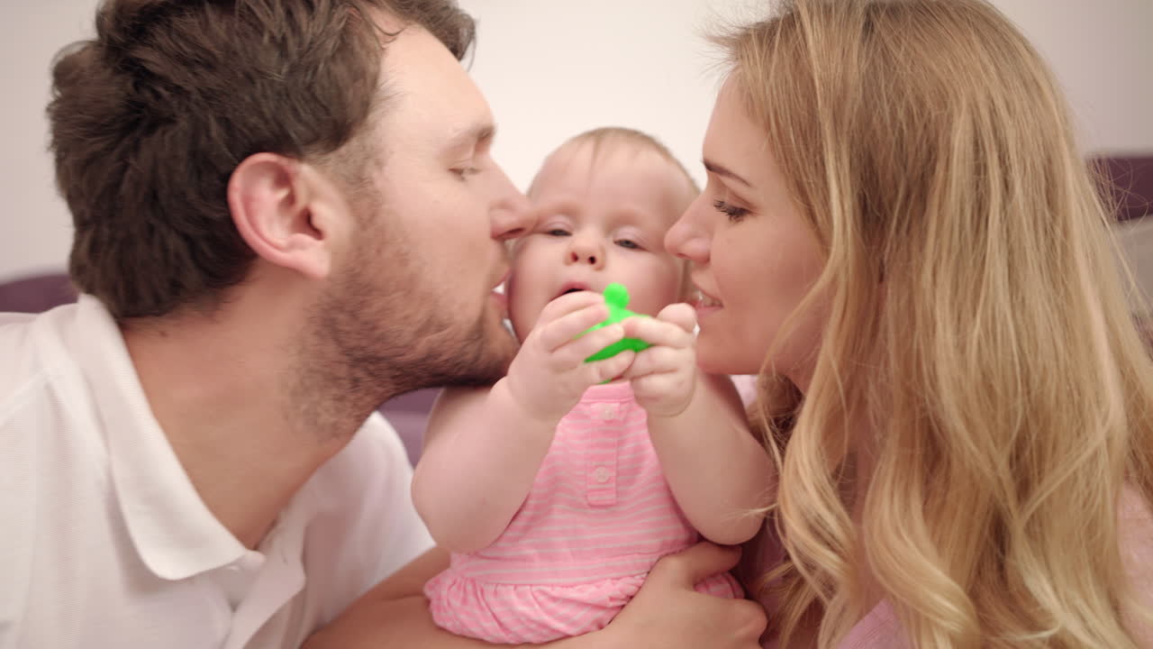 Schöne Familie mit Baby. Süße Familienliebe. Mama und Papa küssen kleines Mädchen.