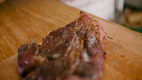 zoom in a close-up view of hot juicy and smoky marinated steak on a wooden table