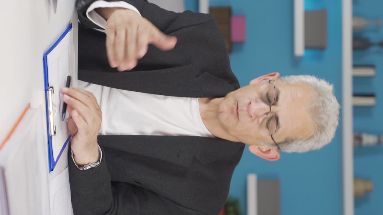 홈 오피스 직원 남자가 나쁜 소식을 읽고 좌절감을 느끼는 수직 비디오입니다.