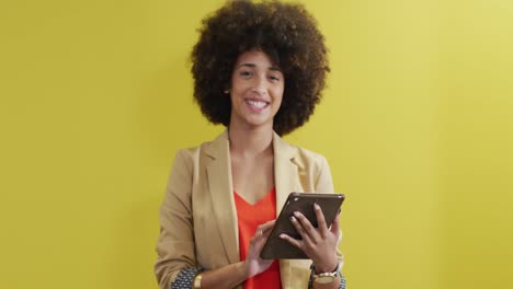 Video-of-happy-biracial-woman-looking-at-camera-on-yellow-background