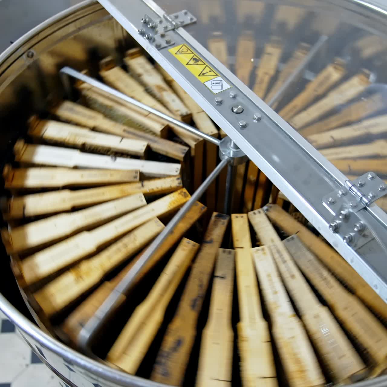 Centrifuge device pumping honey from cells. Honey extractor is spinning with frames with honeycombs. Process of getting honey from honeycomb