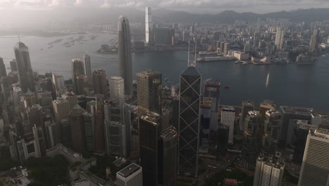 Downtown-Central-financial-district,-with-iconic-IFC-and-Bank-of-China---Kowloon-district-in-background-during-bright-day---Drone-panning-shot