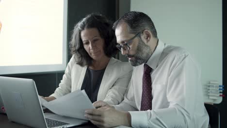 caucasian businesspeople sitting and checking documentation