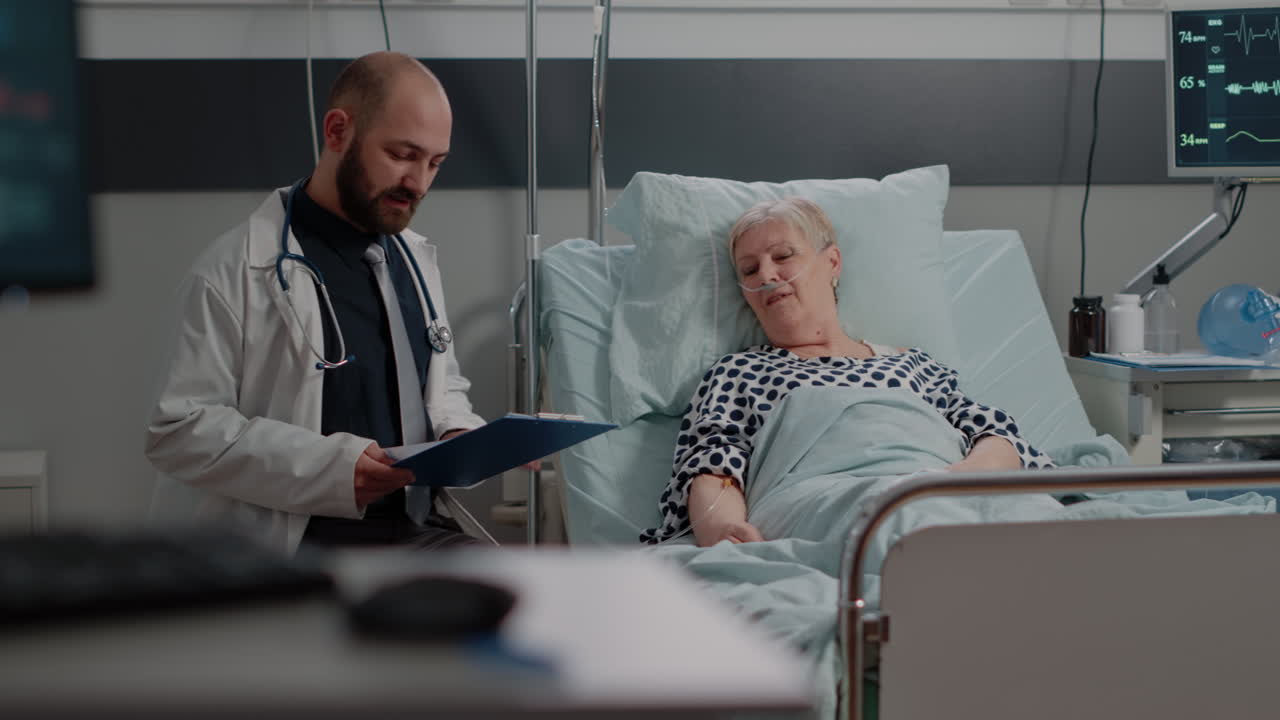 Doctor doing consultation with senior patient in hospital ward