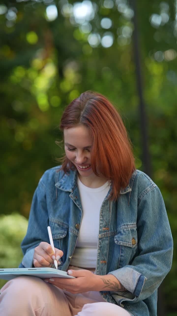 Donna che disegna su un tablet digitale in un parco