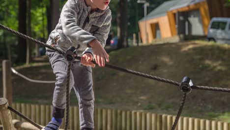 Ein-Kleiner-Junge-Spielt-Auf-Einem-Spielplatz,-Klettert-Auf-Seile-Und-Holz-Und-übt-Sein-Gleichgewicht-In-Einem-Abenteuerpark