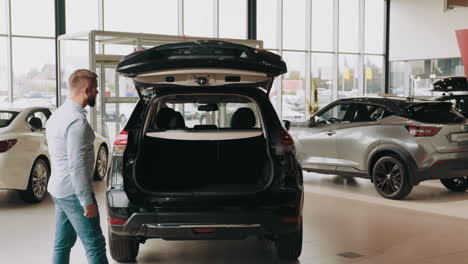 cliente comprobando el maletero de un suv negro en un concesionario de automóviles