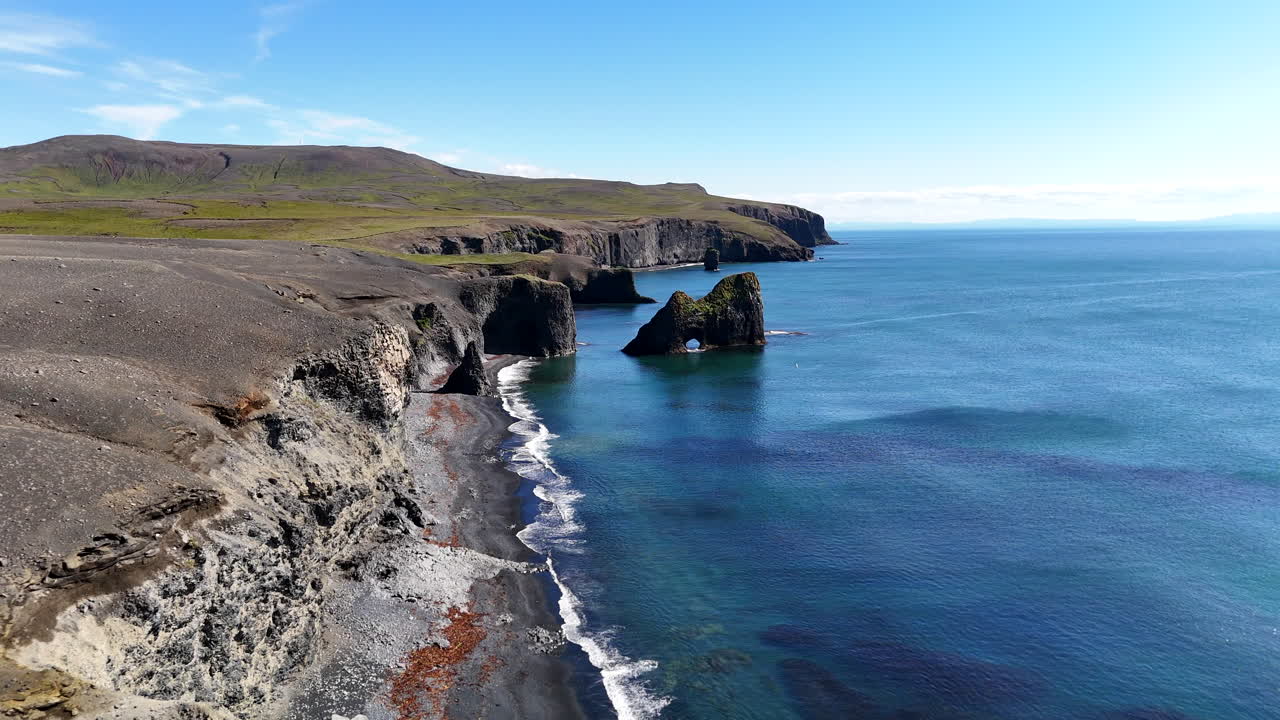 Vista aérea de la costa de Kópasker con un arco de roca natural, que muestra costas escarpadas, olas oceánicas y paisajes naturales del norte de Islandia a plena luz del día