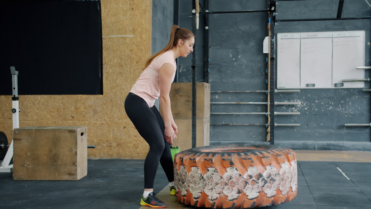 Woman Performing Tire Flip Exercise in Gym