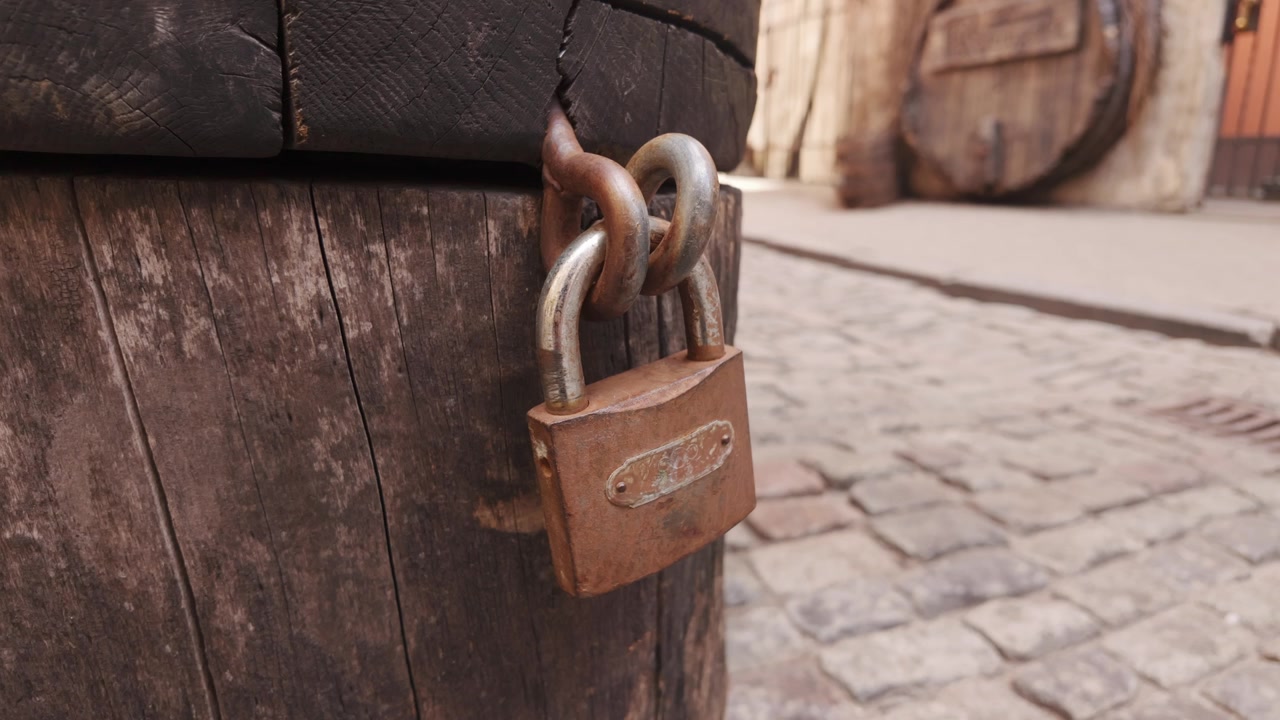 Close-up of a rusty padlock attached to weathered wooden barrel in Riga Old Town