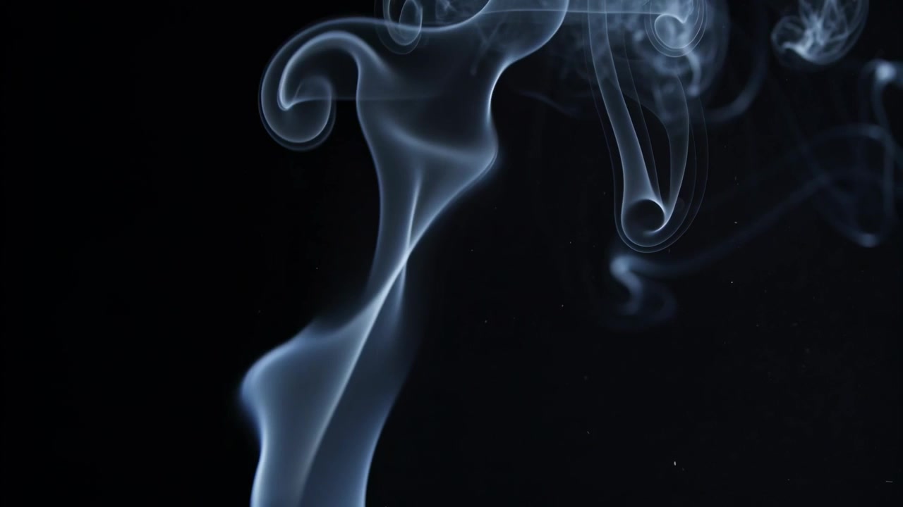 Colonna di fumo bianco-blu che sale, originando sotto l'inquadratura, arricciandosi in volute su uno sfondo scuro.