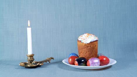 arreglo de pascua, pascua en el plato blanco con huevos teñidos, cerca de la vela blanca ardiente