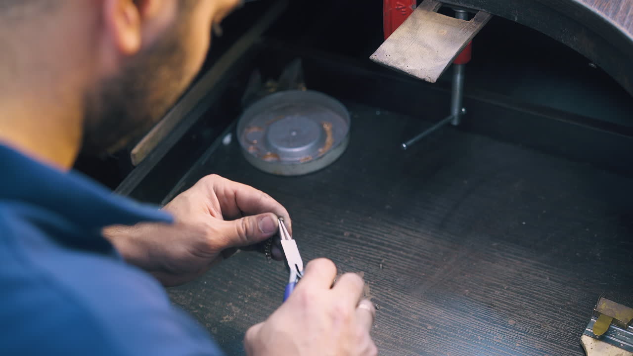el orfebre hace una cadena con pequeños enlaces por encima de la mesa