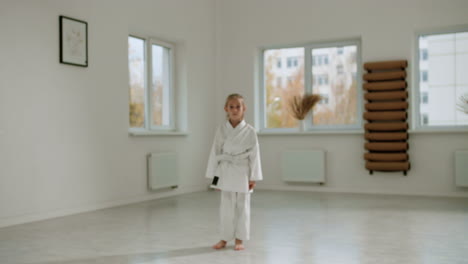 chica en kimono blanco en la clase de artes marciales