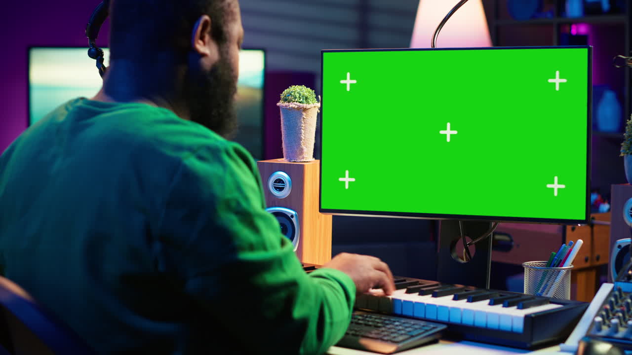 Musician operates on midi controller piano keys next to mockup screen