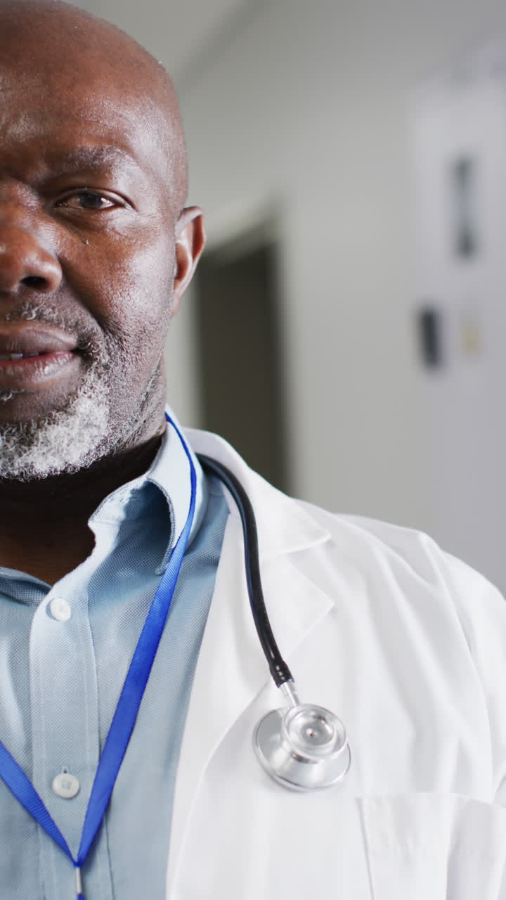 Vertical video of portrait of happy african american male doctor