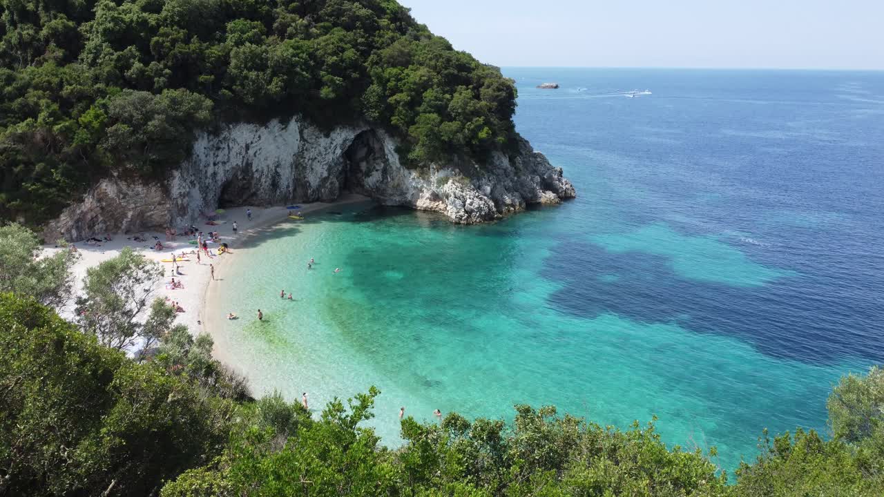 Rovinia beach aerial view over white sand, crystal clear waters and people sunbathing in Corfu, Greece. Dolly in drone flight