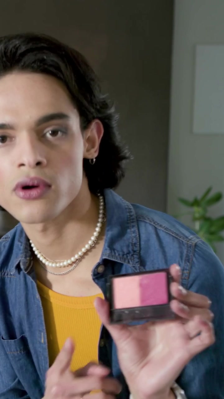 Vertical video: Facing camera, man in yellow top showing blush compact and palette to teach at home