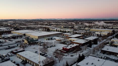 sunrise over calgary's industrial warehouses with rocky mountains in the background