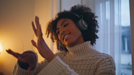 Headphones-girl-enjoying-music-at-evening-flat.-Close-up-african-lady-dancing