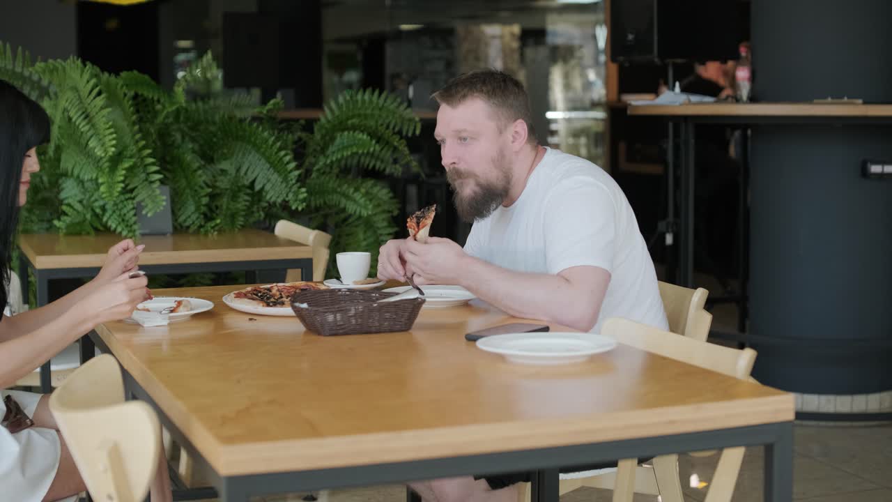 una pareja comiendo pizza en un restaurante.