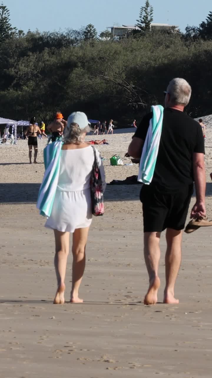 다른 사람 들 과 함께 해변 에서 고 있는 두 사람