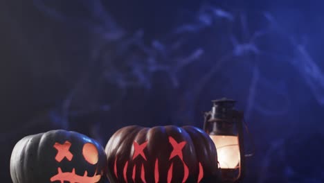 Vídeo-De-Calabazas-Talladas-De-Halloween,-Velas-Y-Humo-Con-Espacio-Para-Copiar-Sobre-Fondo-Azul