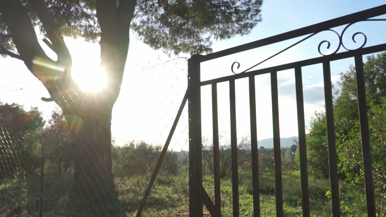 deslice la toma de paralaje de la vieja puerta de barandilla oxidada en los campos, con la montaña parnitha en el fondo