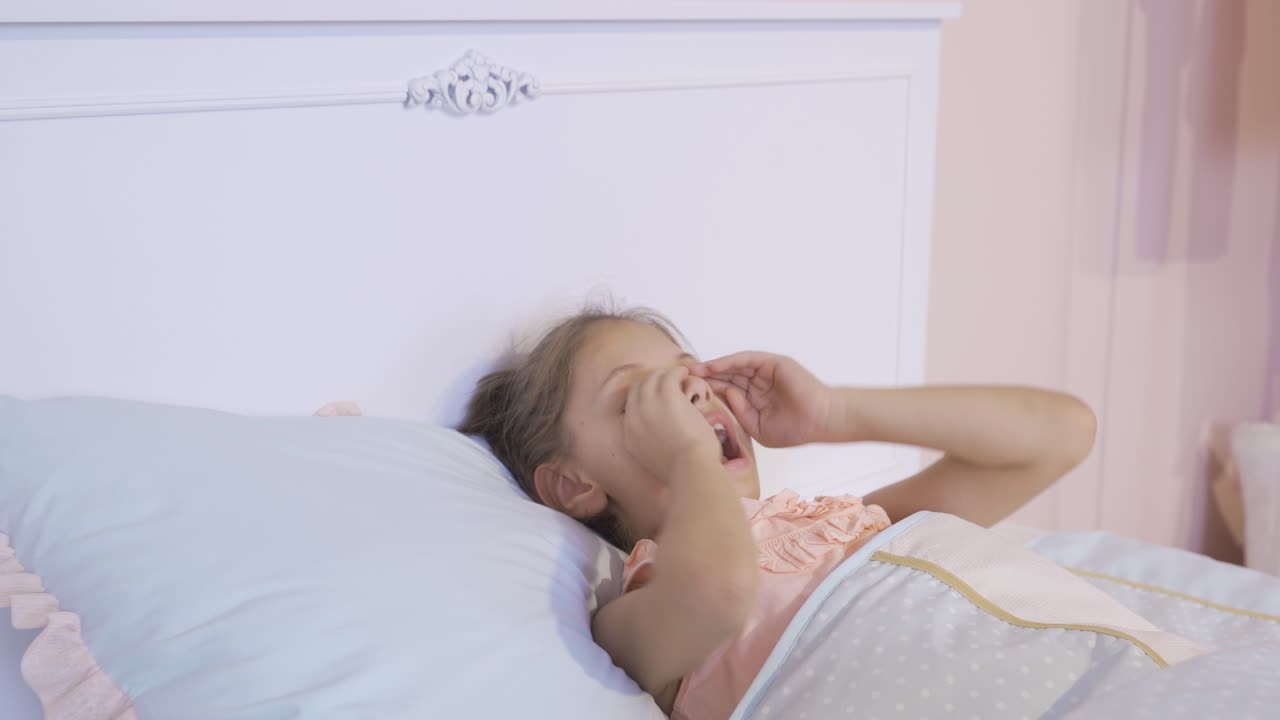 어린 소녀가 아침에 깨어납니다.