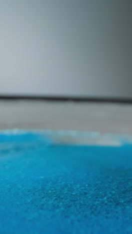 pile of blue hydrophobic sand lies on convex rounded surface on gray background. bright small particles for creation decorative elements and children games macro