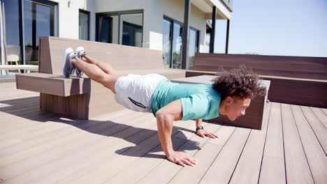 un hombre biracial en forma está haciendo flexiones en un banco en el patio trasero de casa