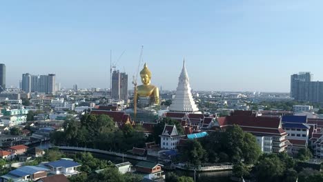 big golden buddha sitting in a city landscape, wat paknam under construction