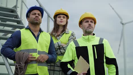 retrato de un grupo de equipos de pie orgullosos frente al molino de viento.