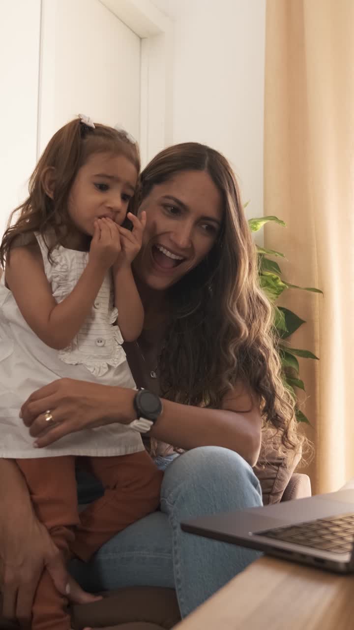 Madre e figlia sorridenti che usano un netbook sul divano a casa.