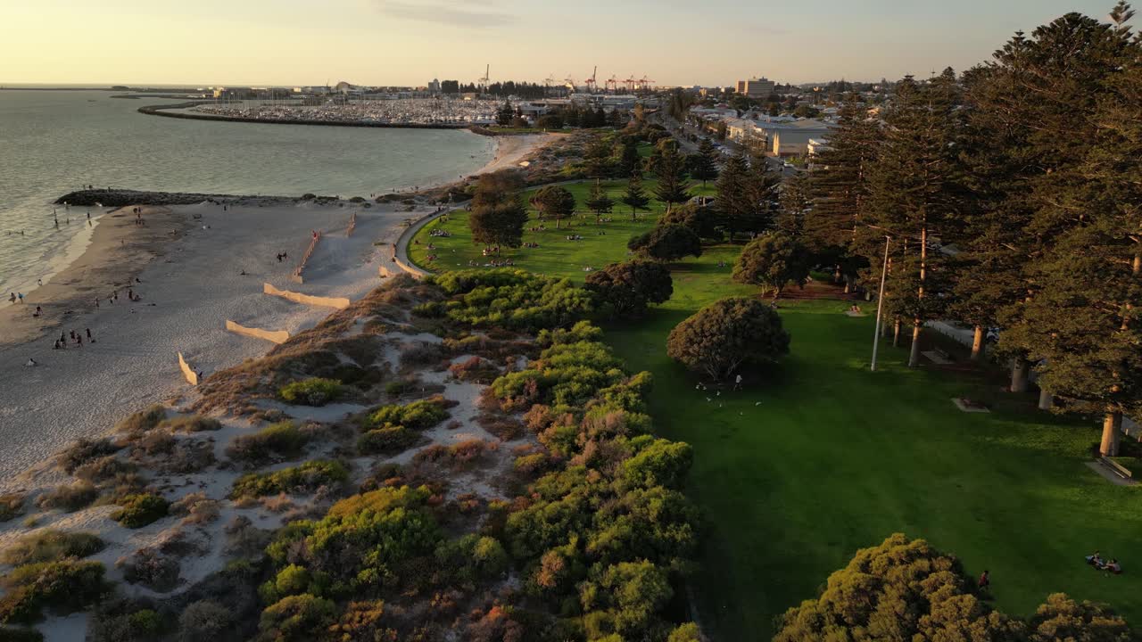 오스트레일리아 서부 프리맨틀 의 모래 모래 해변 과 사우스 비치 공원 위 에 드론 을 비행 시키는 항공기 - 골든 선 ⁇  중 배경 에 있는 항구 항구