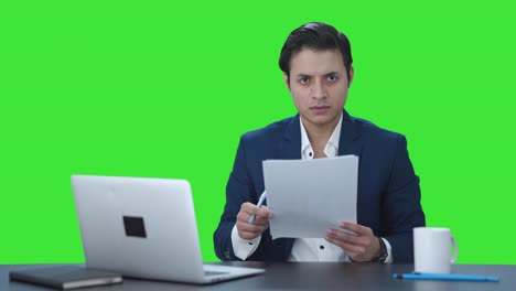 gerente indio enojado leyendo y firmando informes pantalla verde