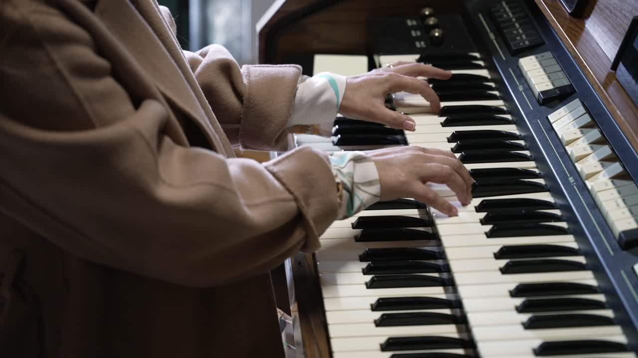 close up of hands playing double keyboard on electric organ