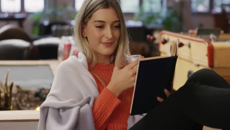 caucasian woman drinking coffee and reading a book