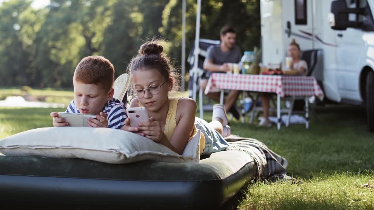 Video med sporing mod højre af børn med telefon på campingferie