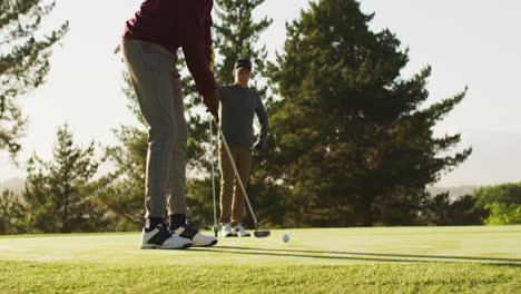 video of diverse male friends playing golf on golf field