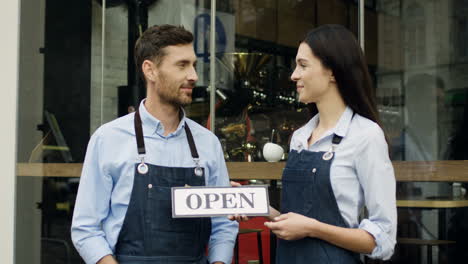 Buena-Mujer-Y-Hombre-Sonrientes,-Trabajadores-Del-Restaurante,-Parados-En-La-Calle-En-La-Puerta-Mirándose-Unos-A-Otros-Y-Luego-A-La-Cámara