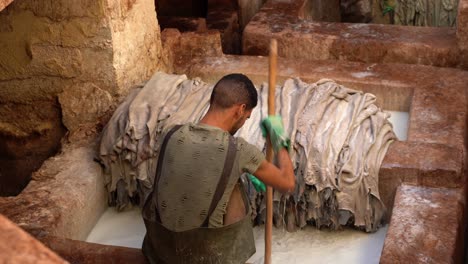 un hombre de atrás mientras trabaja en una curtiduría en fez, marruecos