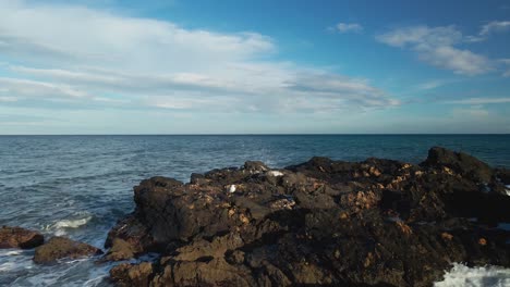 Drone-slowly-moving-forward-at-an-ocean-rock