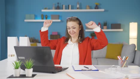 una mujer que trabaja en una oficina se alegra de lo que ve en la computadora portátil.