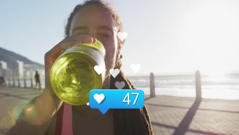 animation of heart icon with numbers over biracial female athlete drinking water against sea